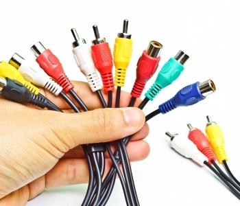a hand holding a bunch of AV cables that are red, yellow, turquoise and white