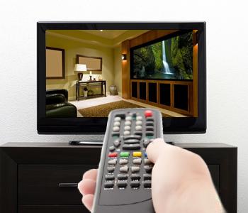 a hand holding a remote turning on a tv