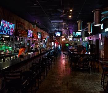 photo of a bar view with the bar and a tv on the left and other seating on the right